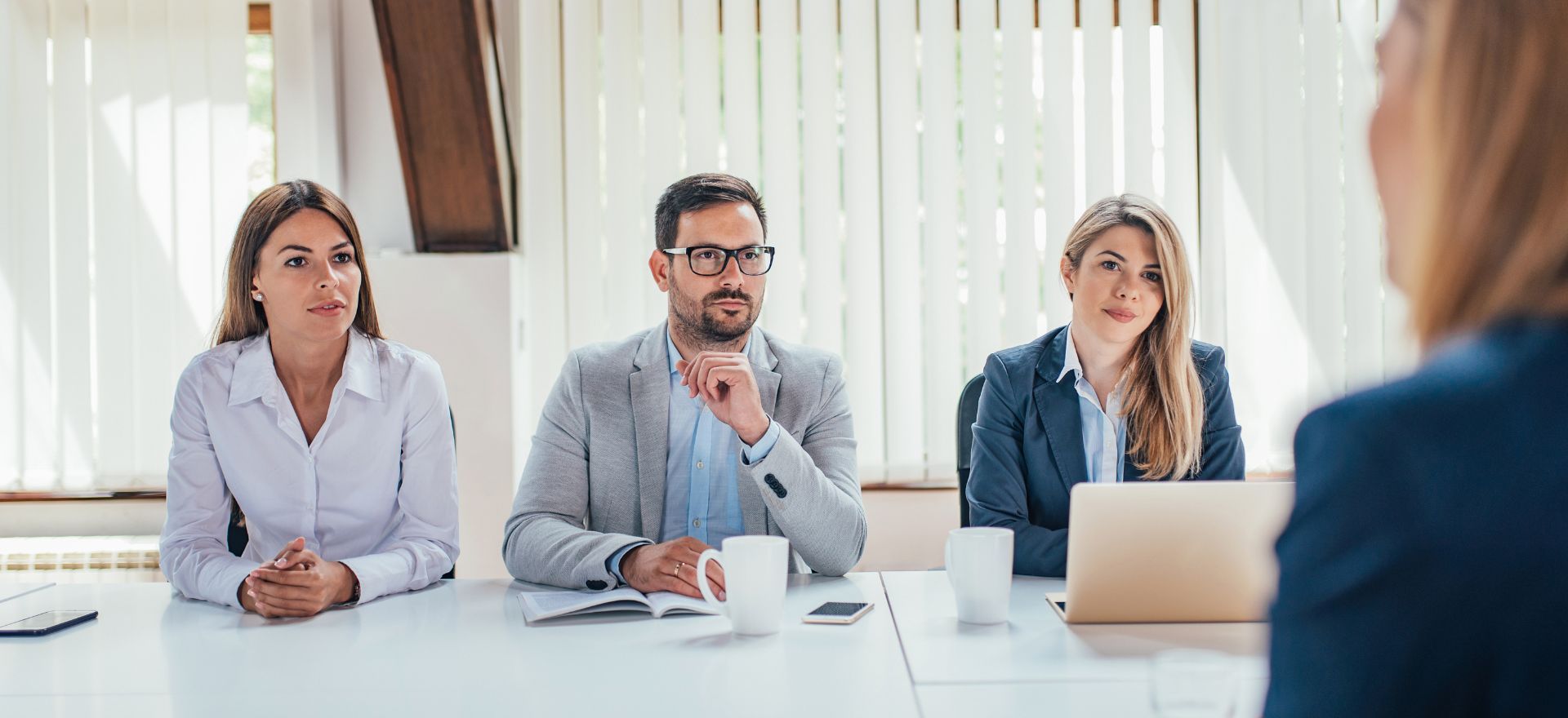 Professional interview setting with three business professionals attentively listening at a table